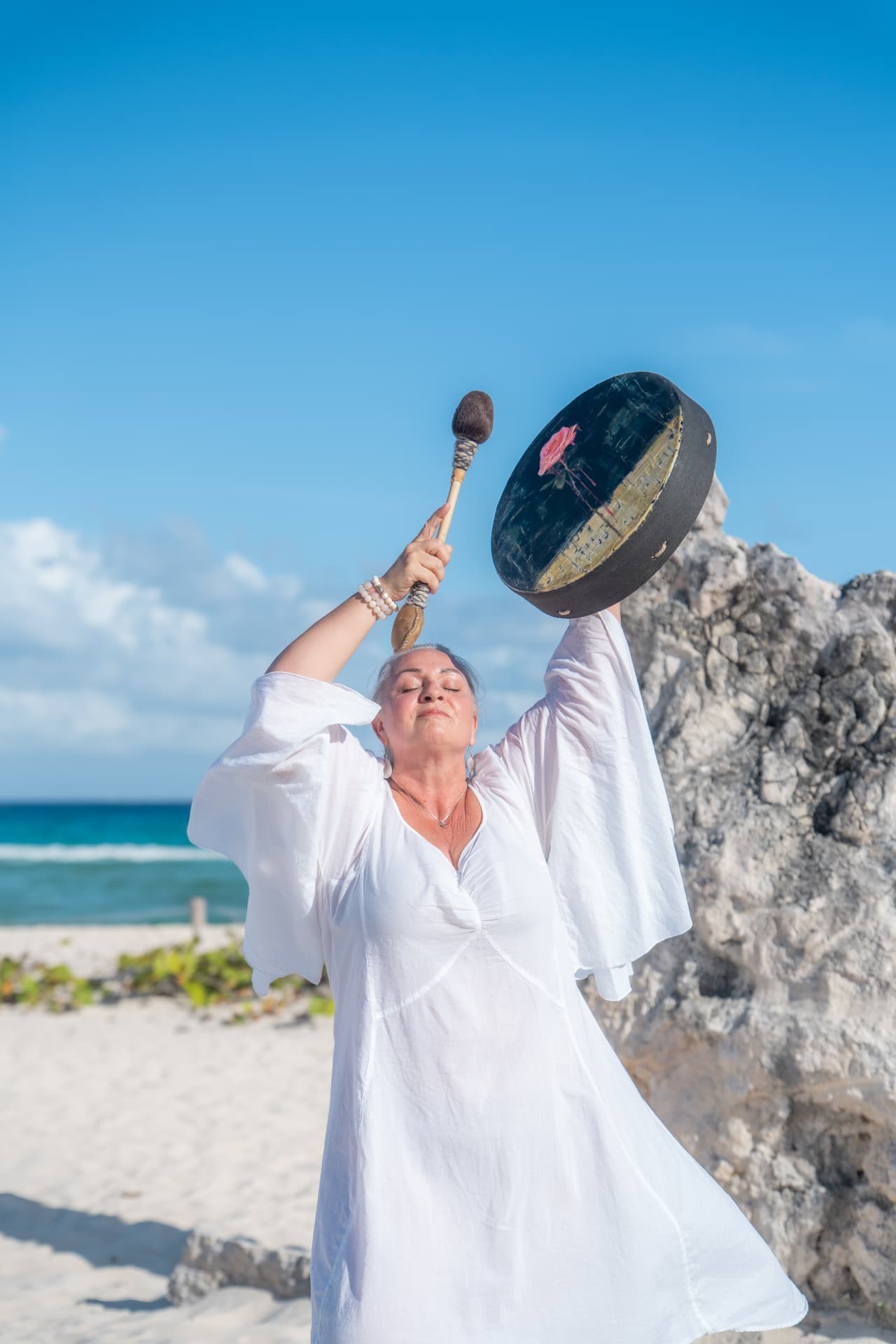 Joya Sosnowski raising a drum by the ocean
